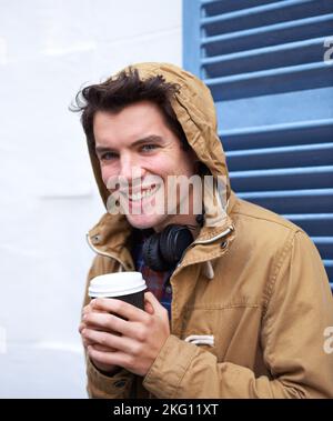 Cher café, vous êtes si beau pour moi. Un beau jeune homme debout à l'extérieur dans le froid buvant une tasse de café chaud. Banque D'Images