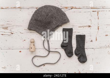 Bonnet beanie et chaussettes en coton biologique pour bébé sur fond blanc en bois Banque D'Images