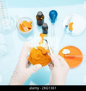 Recherche médicale sur les propriétés de curcuma avec l'aide d'équipements de laboratoire, femme en gants testant la poudre curcuma. Vue de dessus. Banque D'Images