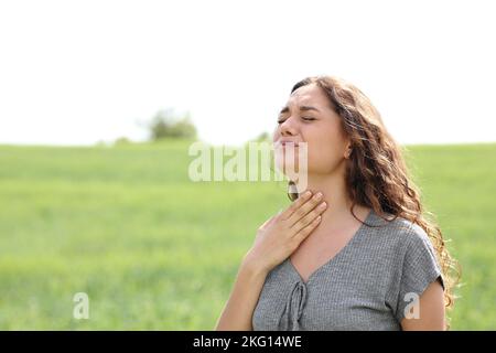 Femme stressée souffrant de mal de gorge dans un champ vert Banque D'Images