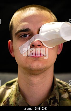 Un Airman des États-Unis, avec l'aile Air Mobility 375th, simule une blessure aux yeux lors du Ballistic Badger 2022 sur la base de la Garde nationale aérienne Volk Field, Wisconsin, le 21 octobre 2022. Des aviateurs ont été transportés d'un C-17 Globemaster III dans le cadre d'une simulation d'évacuation aéromédicale qui a permis aux patients blessés de recevoir des soins médicaux supplémentaires. Banque D'Images