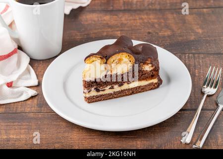 Gâteau avec profiteroles sur une assiette en porcelaine blanche avec café filtre sur le côté Banque D'Images