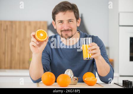 un heureux homme qui boit du jus d'orange Banque D'Images