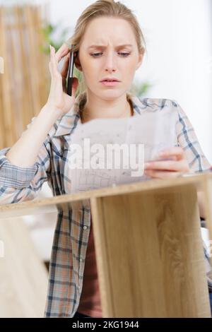 femme au téléphone essayant d'assemprès d'un meuble Banque D'Images