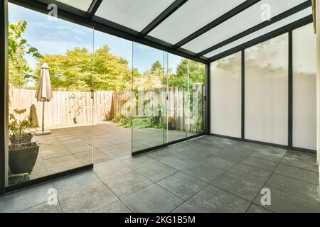 Porte vitrée ouverte donnant sur la terrasse depuis le salon élégant dans une maison moderne et lumineuse Banque D'Images