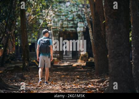 Vue arrière de l'homme avec sac à dos arrivant à l'ancien temple. Voyageur au Cambodge. Banque D'Images