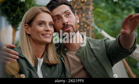 Amoureux couple marié mari et femme caucasien barbu homme et femme blonde 40s conjoints assis à l'extérieur regardant dans la distance rêvant contemplant Banque D'Images