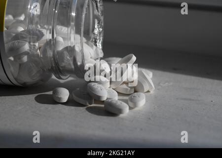 Un gros plan d'une bouteille de pilules qui se répandent sur un comptoir sous le soleil Banque D'Images