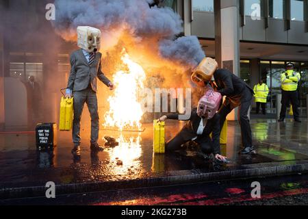 Les activistes de la rébellion océanique manifestent par le vomissement de fausses huiles et par un incendie lors d'une manifestation en dehors de l'Organisation maritime internationale (OMI), dans le centre de Londres, qui coïncide avec une série plus large d'actions visant à réduire les liens avec l'industrie des combustibles fossiles. Date de la photo: Lundi 21 novembre 2022. Banque D'Images