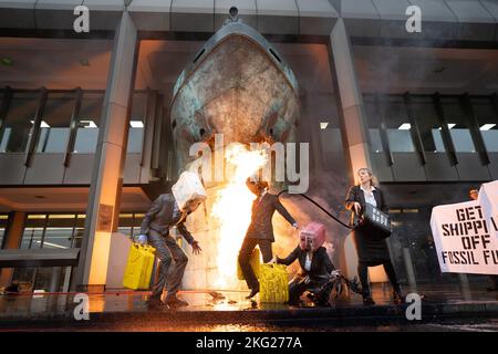 Les activistes de la rébellion océanique manifestent par le vomissement de fausses huiles et par un incendie lors d'une manifestation en dehors de l'Organisation maritime internationale (OMI), dans le centre de Londres, qui coïncide avec une série plus large d'actions visant à réduire les liens avec l'industrie des combustibles fossiles. Date de la photo: Lundi 21 novembre 2022. Banque D'Images