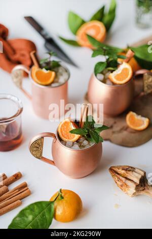 Boissons alcoolisées à base de mandarine et de cannelle dans des mugs en cuivre Banque D'Images