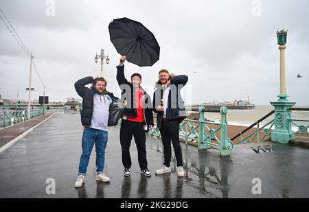 Brighton UK 21st novembre 2022 - les fans d'Angleterre combattent le vent et la pluie sur le front de mer de Brighton en faisant leur chemin à un bar pour regarder le match de la coupe du monde du Qatar entre l'Angleterre et l'Iran aujourd'hui : Credit Simon Dack / Alamy Live News Banque D'Images