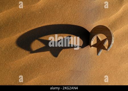 Ombre sur le sable au coucher du soleil d'un croissant et d'une étoile. Symbole de l'Islam et de la spiritualité. Abou Dhabi. Émirats arabes Unis. Banque D'Images