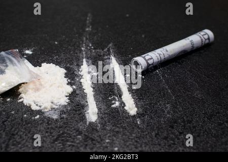 Sac en plastique, deux lignes et un bouquet de cocaïne avec un tube respiratoire avec une facture de cent dollars, sur fond noir, gros plan. Banque D'Images