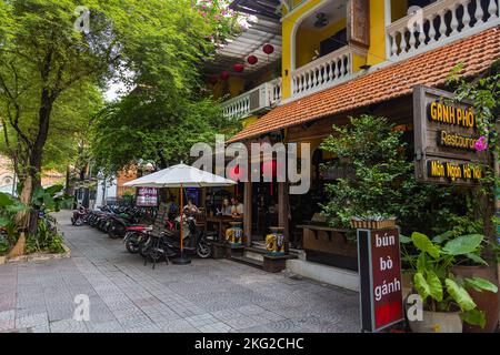 Ho Chi Minh ville, Vietnam - 07 novembre 2022: Café de rue à Saigon. Les touristes s'assoient dans le petit restaurant et mangent de la nourriture locale. Paysage urbain avec traditio Banque D'Images