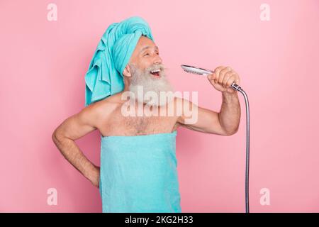 Photo d'homme senior drôle chantant dans le bain utiliser la pomme de douche comme microphone isolé sur fond de couleur pastel Banque D'Images