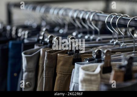 Gros plan des jeans et des pantalons en rangée sur le porte-vêtements du magasin d'occasion, espace de copie Banque D'Images