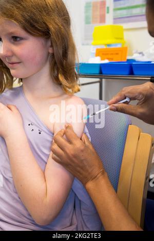 Une jeune fille de 8 ans reçoit le vaccin d'ARNm Comirnarty 10 COVID-19 pour l'inoculer contre l'infection par le delta d'Omicron ou d'autres variantes existantes du coronavirus. L'infirmière administre l'injection au centre de santé local de Teddington. ROYAUME-UNI. (132). L'enfant qui reçoit le vaccin est un modèle libéré. Banque D'Images