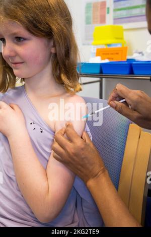 Une jeune fille de 8 ans reçoit le vaccin d'ARNm Comirnarty 10 COVID-19 pour l'inoculer contre l'infection par le delta d'Omicron ou d'autres variantes existantes du coronavirus. L'infirmière administre l'injection au centre de santé local de Teddington. ROYAUME-UNI. (132). L'enfant qui reçoit le vaccin est un modèle libéré. Banque D'Images