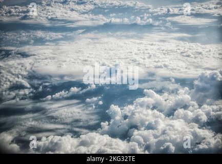 Vue sur le ciel bleu et les nuages moelleux depuis une fenêtre d'avion Banque D'Images