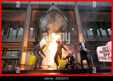 Les militants de la rébellion océanique de PABest manifestent en vomissant de la fausse huile et en provoquant un incendie lors d'une manifestation en dehors de l'Organisation maritime internationale (OMI), dans le centre de Londres, qui coïncide avec une série plus large d'actions visant à réduire les liens avec l'industrie des combustibles fossiles. Date de la photo: Lundi 21 novembre 2022. Banque D'Images