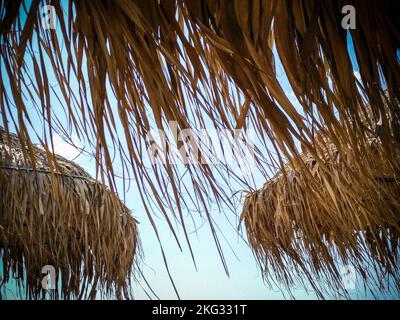 Trois parasols en paille sur une plage vue d'en dessous Banque D'Images