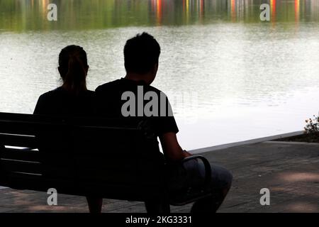 Solsoci d'un homme et d'une femme assis sur un banc. Vue arrière. Hanoï. Vietnam. Banque D'Images