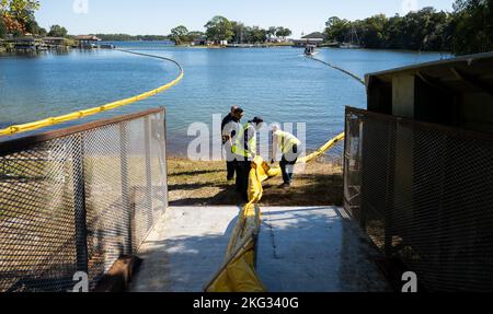 Coast Guardmen et 96th employés du groupe civil Engineer tirent un dispositif de confinement de l'huile connu sous le nom de boom dans l'eau le 26 octobre à la base aérienne d'Eglin, en Floride. L'exercice conjoint a testé les efforts de communication de l'unité locale et les réponses à un important déversement de carburant à Weekly Bayou. Banque D'Images