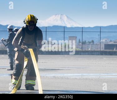 Classe 1st d'Airman Kevin Gutierrez Gonzalez, pompier de l'escadron 374th du génie civil, lance un tuyau d'incendie après un entraînement bilatéral sur un simulateur d'incendie d'avion à la base aérienne de Yokota, Japon, le 26 octobre 2022. La pratique de techniques de lutte contre l'incendie standardisées entre les aviateurs américains et japonais a donné aux deux parties l'occasion d'affiner les capacités communes et de construire des partenariats plus solides. Banque D'Images