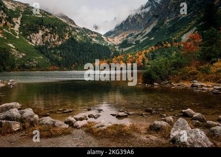Magnifique lac de montagne Popradske pleso avec ses reflets Forêt d'automne, Hautes Tatras en arrière-plan Banque D'Images