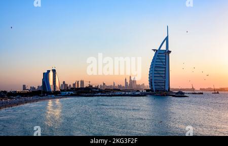 Jumeirah Beach Hotel et l'emblématique Burj Al Arab Hotel avec des ballons d'air chaud passant derrière lui à l'heure du coucher du soleil, Dubaï, Émirats arabes Unis Banque D'Images