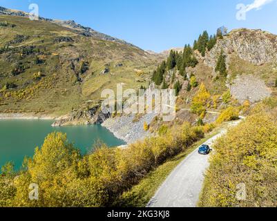 Tir de drone de voiture passant par le lac Beaufortain, une destination cachée dans les alpes de Savoie, France Banque D'Images
