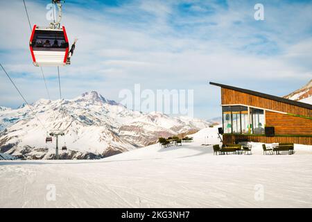 Cabine de remontée mécanique fermée rouge blanc avec skieurs et arrière-plan spectaculaire des montagnes enneigées blanches. La station de ski rouvre. Vacances d'hiver en Géorgie à Gudaur. Kobi Banque D'Images