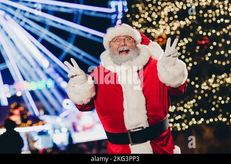 Portrait de père noël funky excité deux mains doigts démontrer V-sign Profitez de nouvelles lumières de temps à l'extérieur Banque D'Images