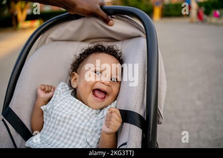 Un parent attentionné qui secoue son bébé souriant dans une poussette Banque D'Images