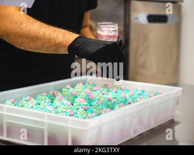 chef pâtissier préparant un bouquet de petits gâteaux givrés sur le thème de la mer turquoise vert Banque D'Images