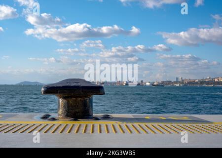 Borne d'amarrage en métal noir dans la marina et le terminal portuaire. Paysage urbain Noray en arrière-plan. Copier les espaces. Banque D'Images