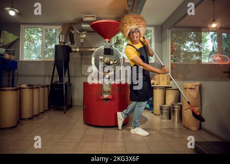 Un jeune employé de café joyeux qui fait le ménage Banque D'Images