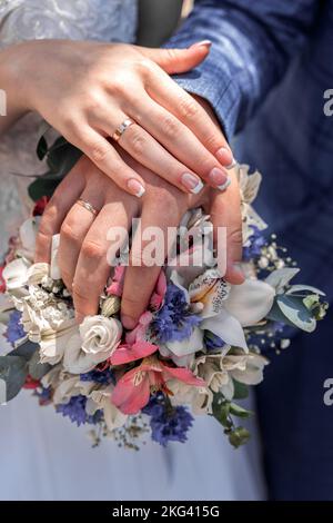 les jeunes mariés présentent des anneaux et un bouquet de fleurs Banque D'Images