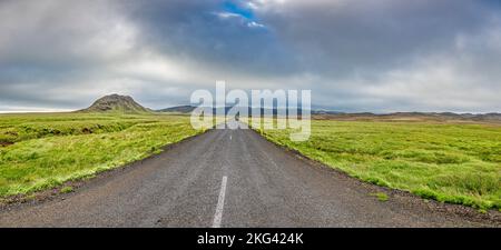 Continuez tout droit sur la route lonely en traversant la prairie sur l'Islande Banque D'Images