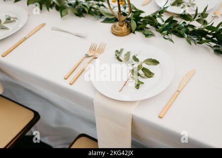 Ensemble de table élégant pour un repas de mariage avec des couverts dorés et du linge blanc Banque D'Images