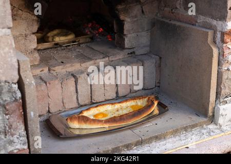 Khachapuri (cuisine géorgienne) adjarienne maison, adossée à un four en briques Banque D'Images