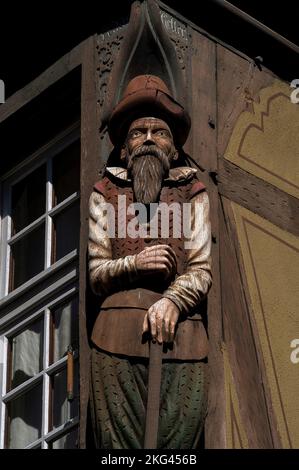 Le Drapier, un marchand de tablier ou de tissu en bois sculpté datant de début 1600s, repose sa main gauche sur un bâton ou une tige de mesure au coin de la Maison zum Kragen (Maison du collier) au 9 rue des Marchands, dans le coeur historique de Colmar, Alsace, Grand est, France. La maison a été construite en 1419, mais s'est effondrée en 1586 et a dû être reconstruite. Banque D'Images