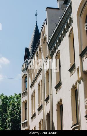 mur blanc d'un bâtiment résidentiel avec fenêtres voûtées en bois et toit d'une tour de château. Banque D'Images