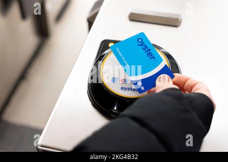 Une femme présente une carte à puce transport for London Oyster sur un lecteur de carte à la porte d'entrée d'une station de métro de Londres. Banque D'Images