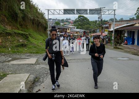 Filandia, Quindio, Colombie - 5 juin 2022: Une femme colombienne de grande taille marche à côté d'une femme péruvienne courte, avec une famille derrière eux Banque D'Images