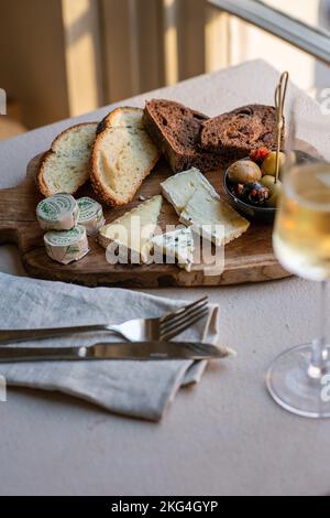 Un cliché vertical de différents types de fromage et de pain sur un plateau en bois Banque D'Images