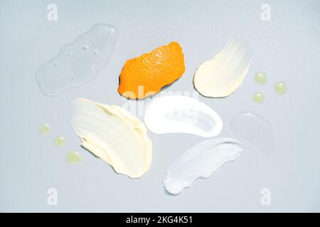 De nombreux échantillons de produits cosmétiques avec de la vitamine C - crème et gel frottis, l'huile tombe sur fond gris clair. Texture taches de crème. Soins antiâge pour la peau Banque D'Images