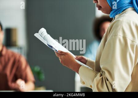 Gros plan de la jeune femme musulmane avec rapport de production de documents lors d'une conférence ou d'un séminaire, tout en se tenant contre le public Banque D'Images