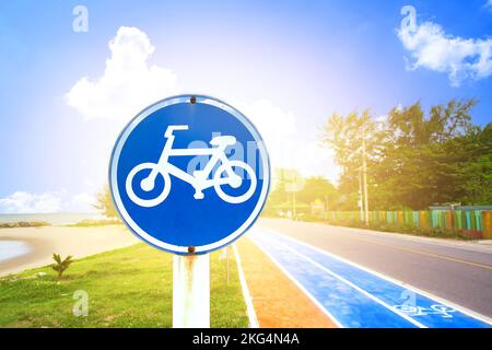 Panneau bleu d'avertissement de piste cyclable sur la plage avec lumière du soleil dans la journée. Banque D'Images